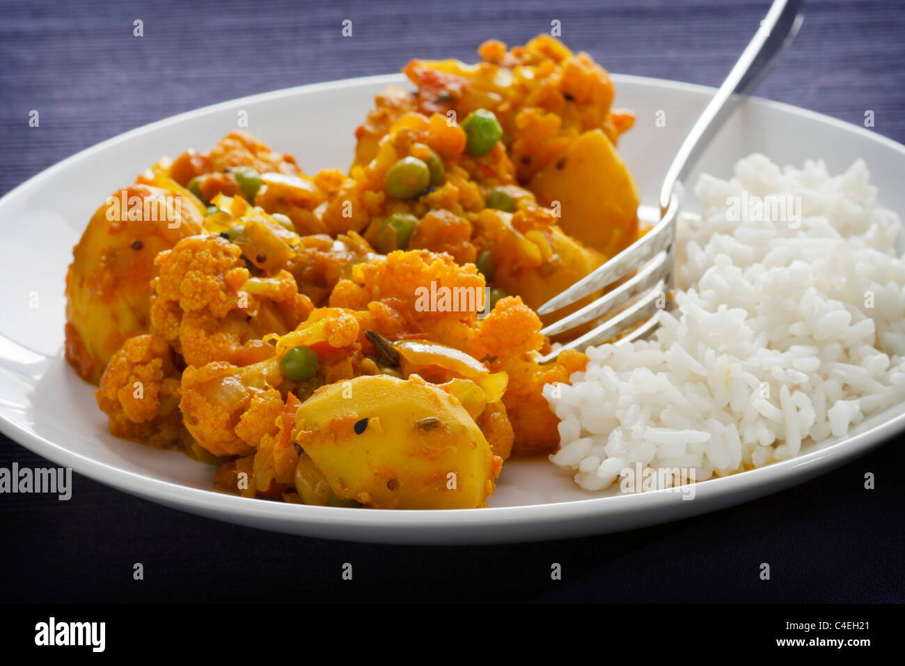 Curry végétarien indien fait à partir de chou-fleur, les pommes de terre et les pois, servi avec du riz. Banque D'Images