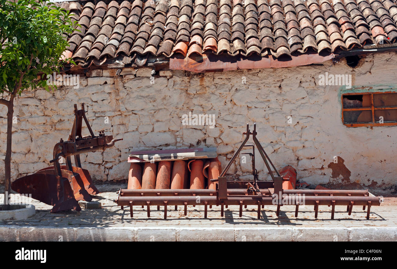 Ancien matériel de ferme en face de bâtiment de ferme Banque D'Images