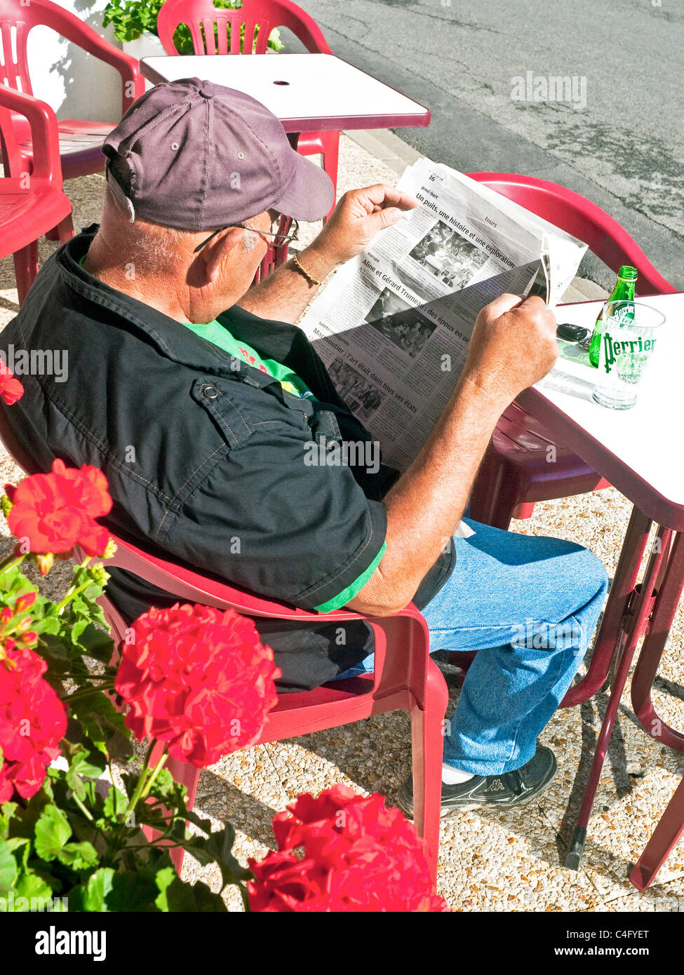 Man reading newspaper at outdoor bar / cafe table - France. Banque D'Images