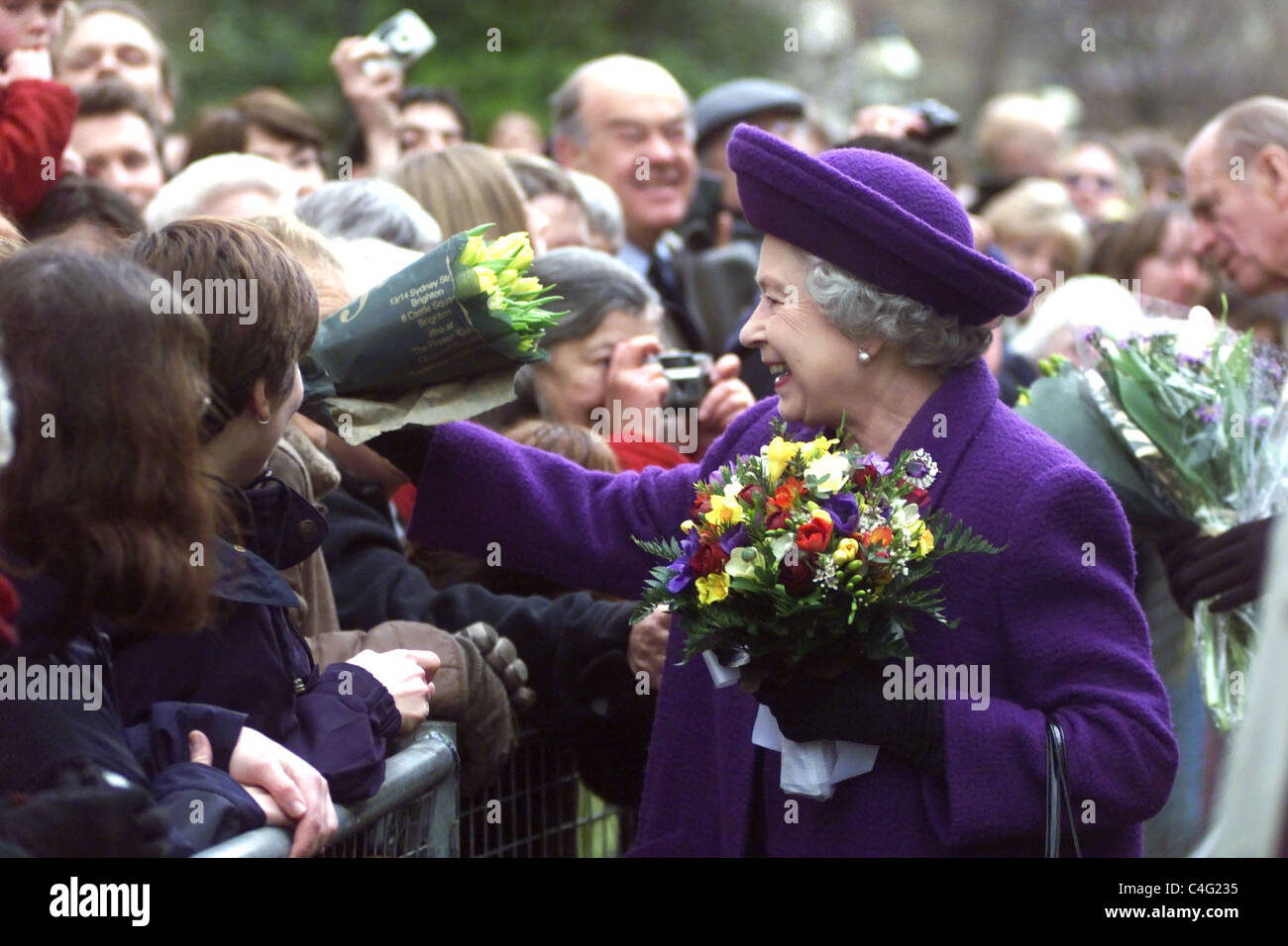 La Reine dans l'humeur joyeuse alors qu'elle répond à la foule qui attendait son marais avec des fleurs près de la porte de l'Inde à Brighton UK- Banque D'Images