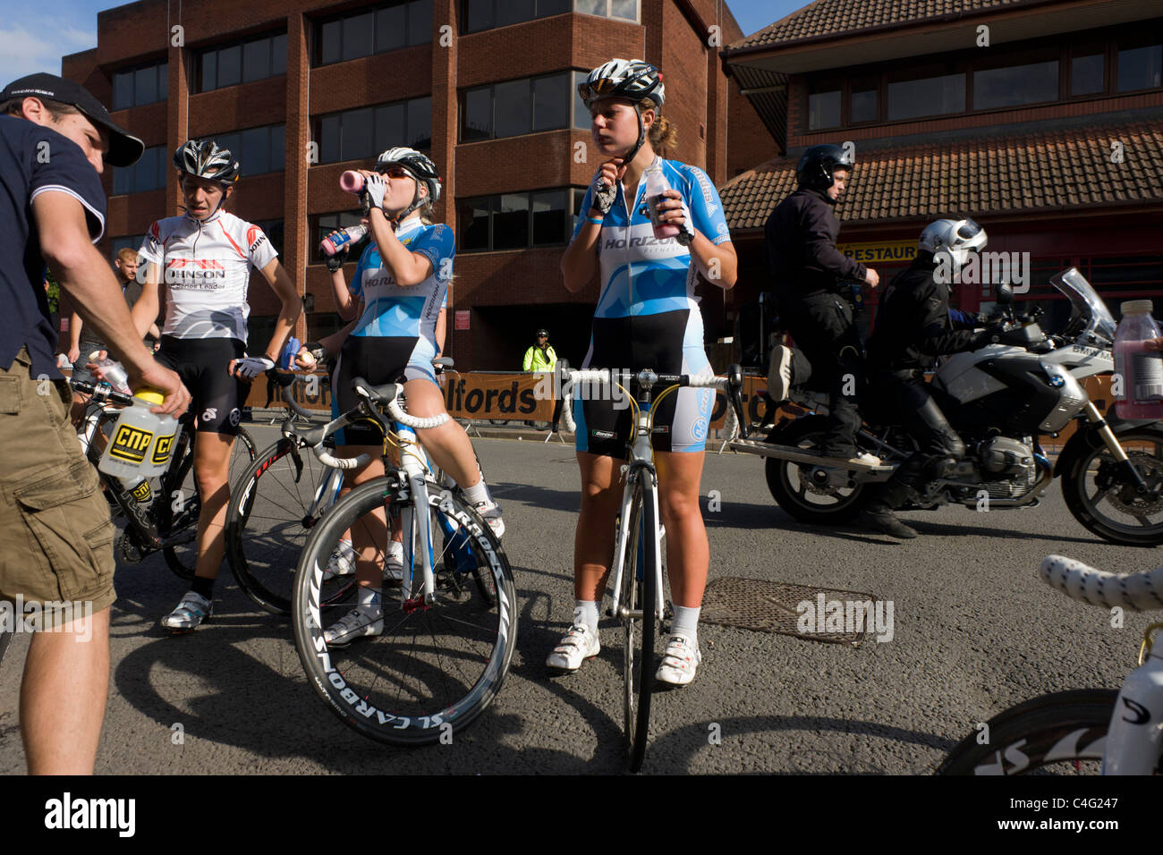Les membres de l'horizon des femmes remise en forme de l'équipe cycliste de course vous détendre après la compétition à Woking rues. Banque D'Images