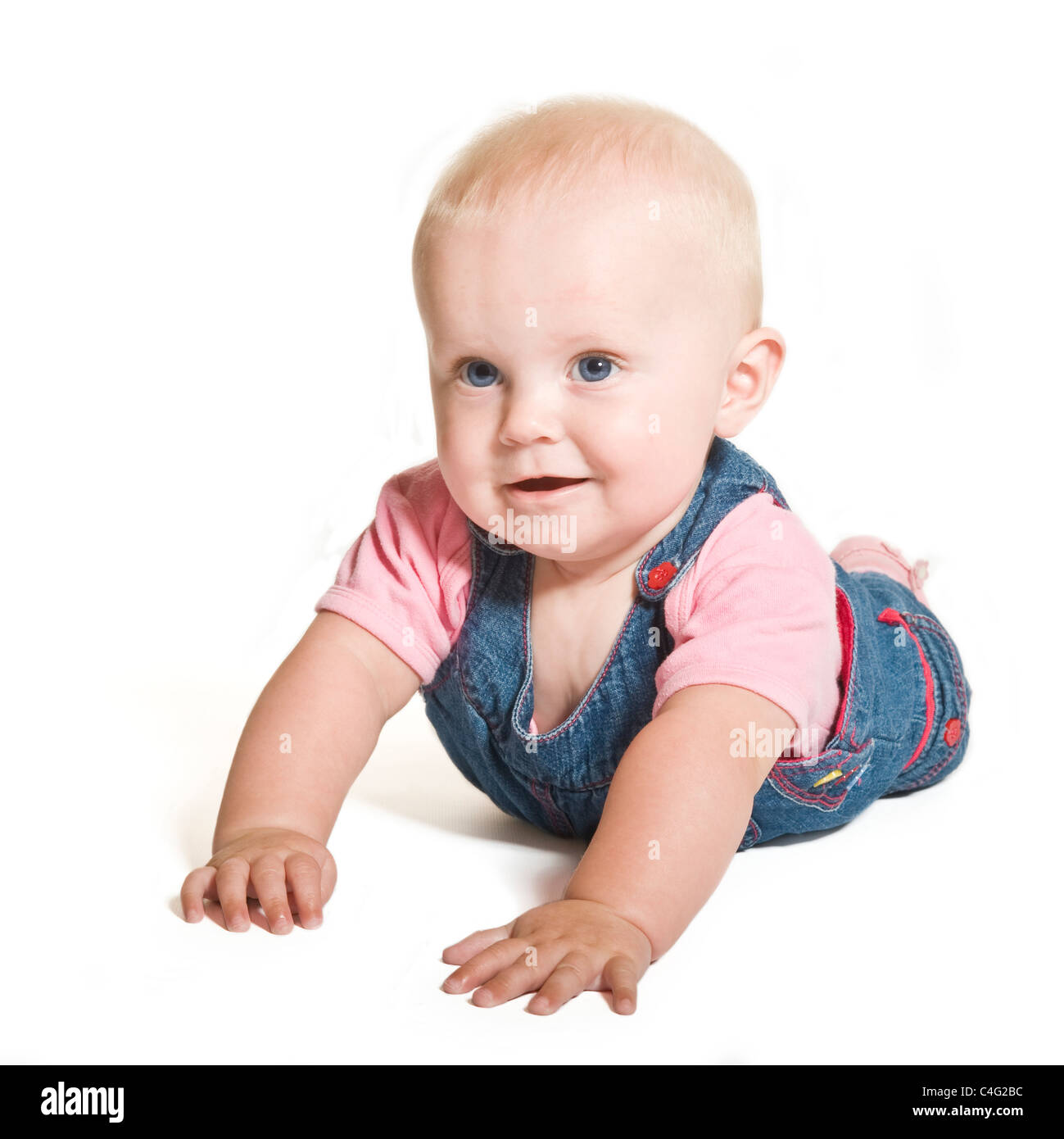 Un mignon bébé de 1 an fille aux yeux bleu denim et porter contre un sourire rose blanc pur (255) Contexte. Banque D'Images