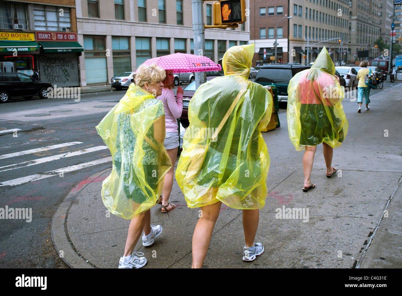 Les touristes dans le Lower Manhattan à New York à pied à travers la pluie dans leurs slickers Banque D'Images