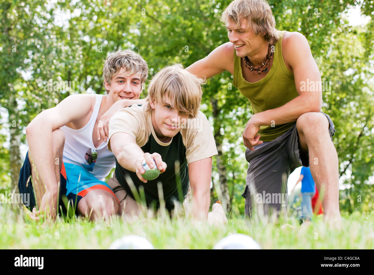 Groupe de jeunes hommes jouant aux boules dans un parc extérieur en été Banque D'Images