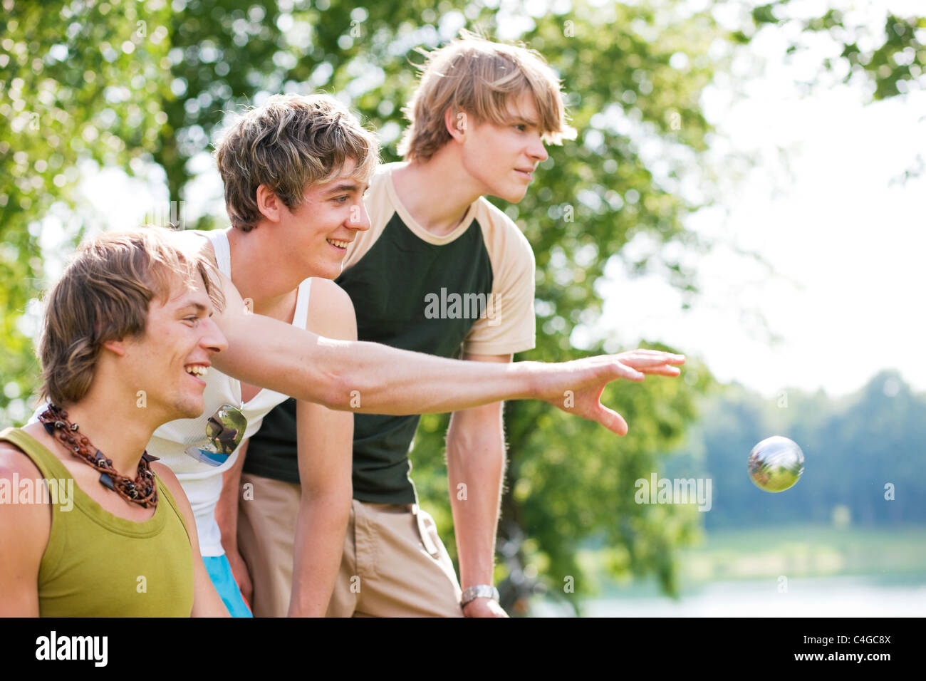 Groupe de jeunes hommes jouant aux boules dans un parc extérieur en été Banque D'Images