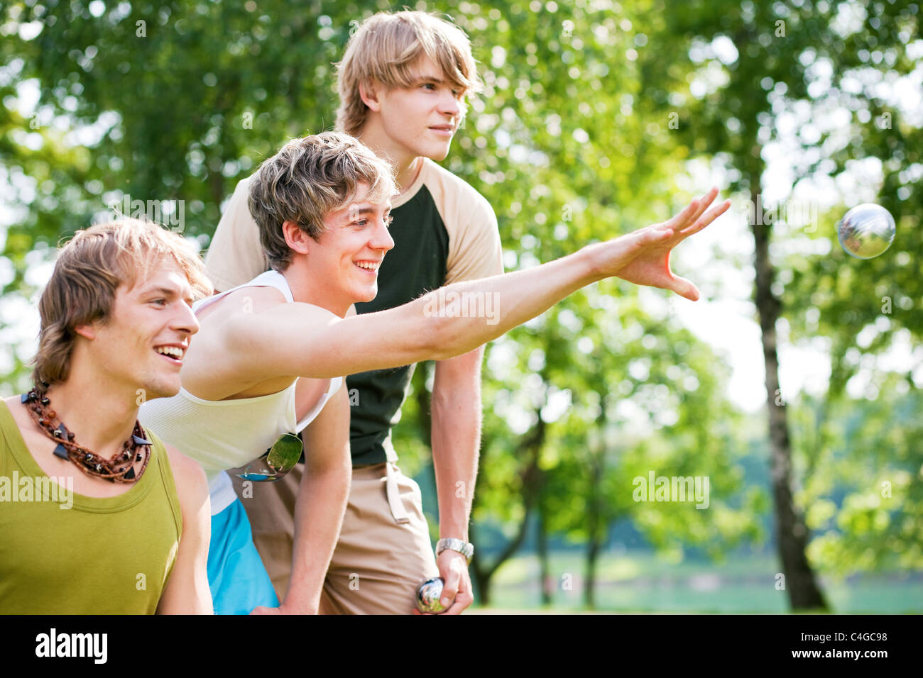 Groupe de jeunes hommes jouant aux boules à un lac à l'extérieur en été Banque D'Images