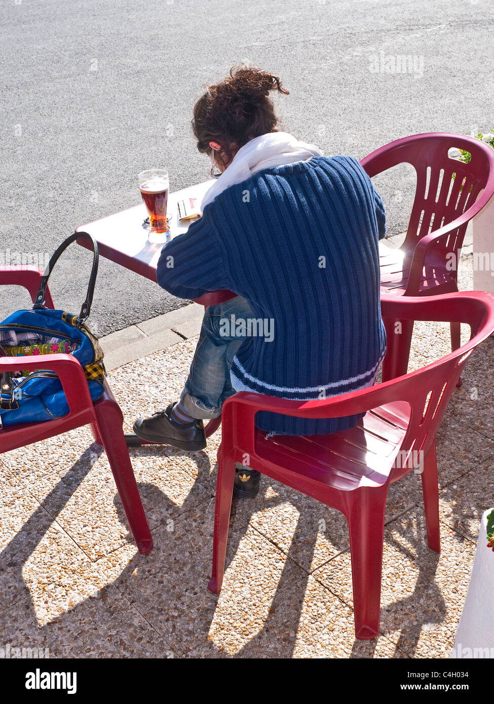 Lecture / écriture de Femme au bar en plein air / cafe table - France. Banque D'Images