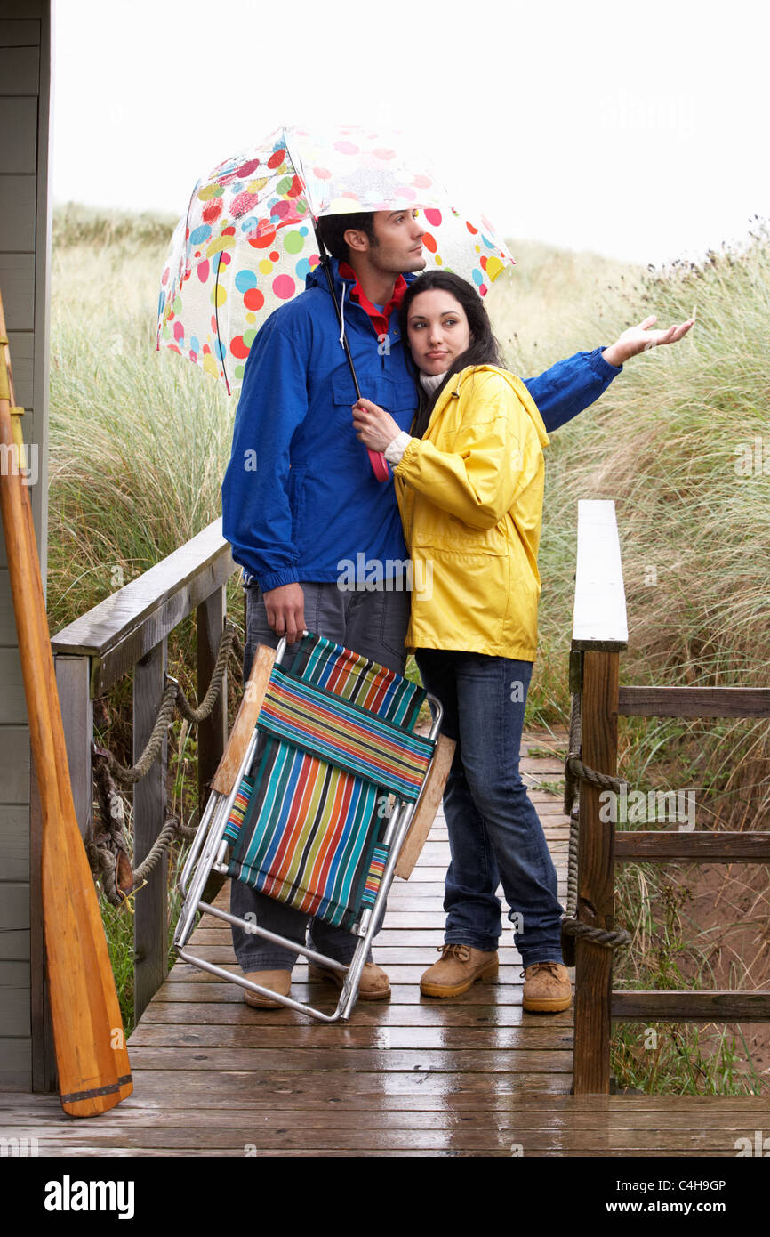 Jeune couple sur plage avec parasol Banque D'Images
