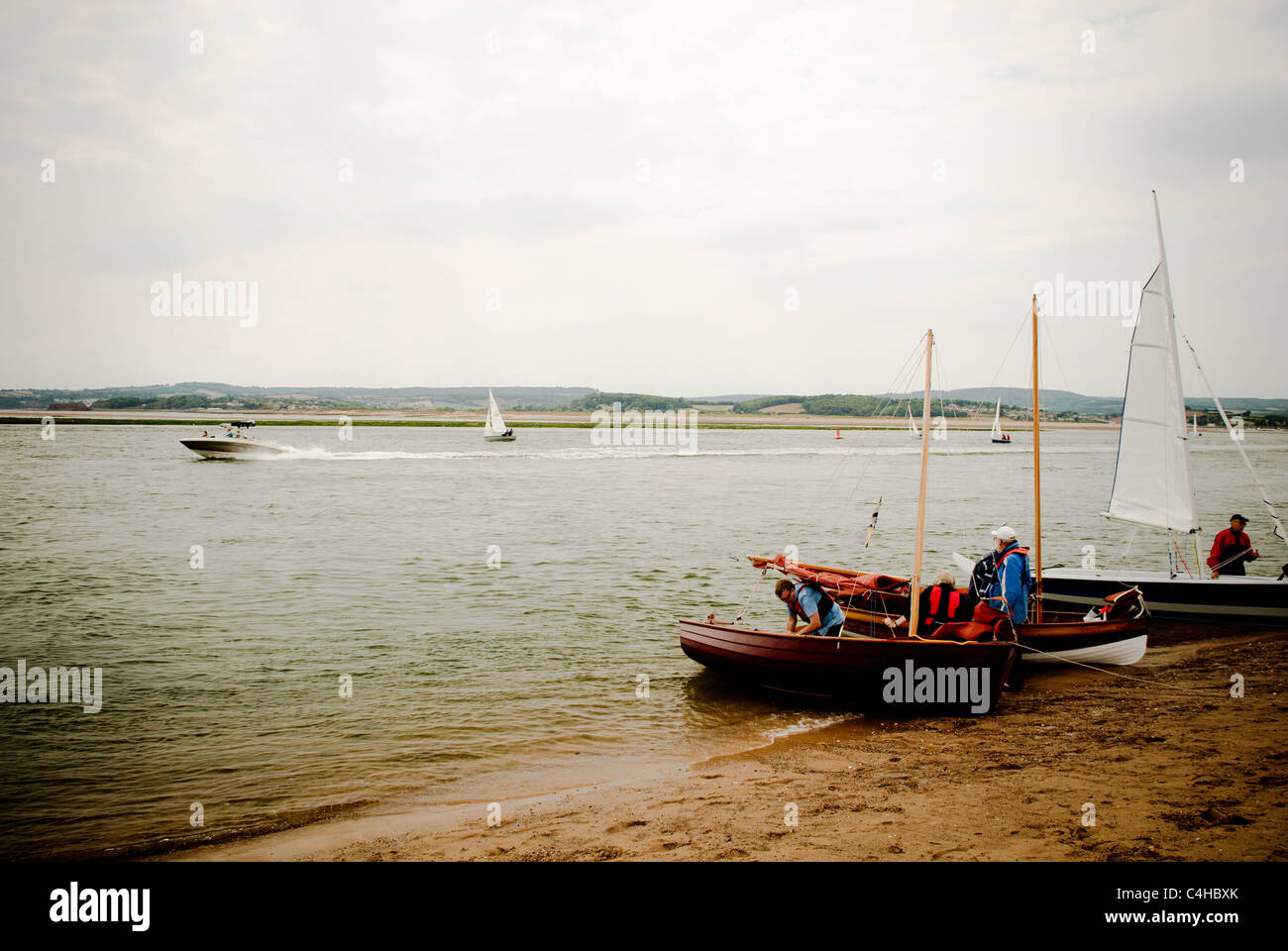 Bateaux amarrés à Exmouth sur plage avec un bateau à moteur et bateaux à voile à l'arrière-plan, Devon, England UK Banque D'Images