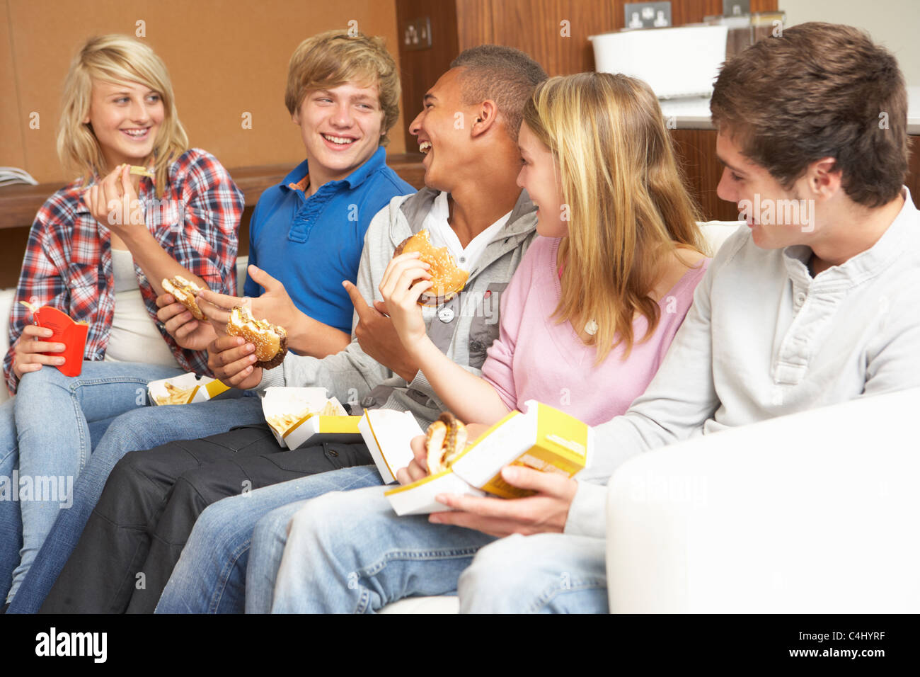 Group of Teenage Friends Sitting on Sofa At Home Eating Fast Foo Banque D'Images