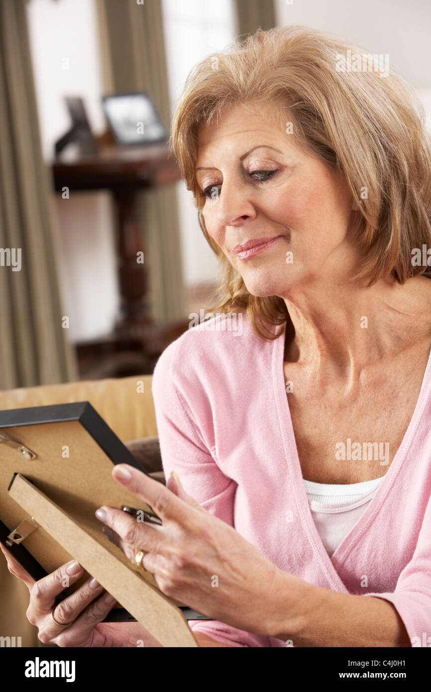 Senior Woman Looking At Photograph in Frame Banque D'Images