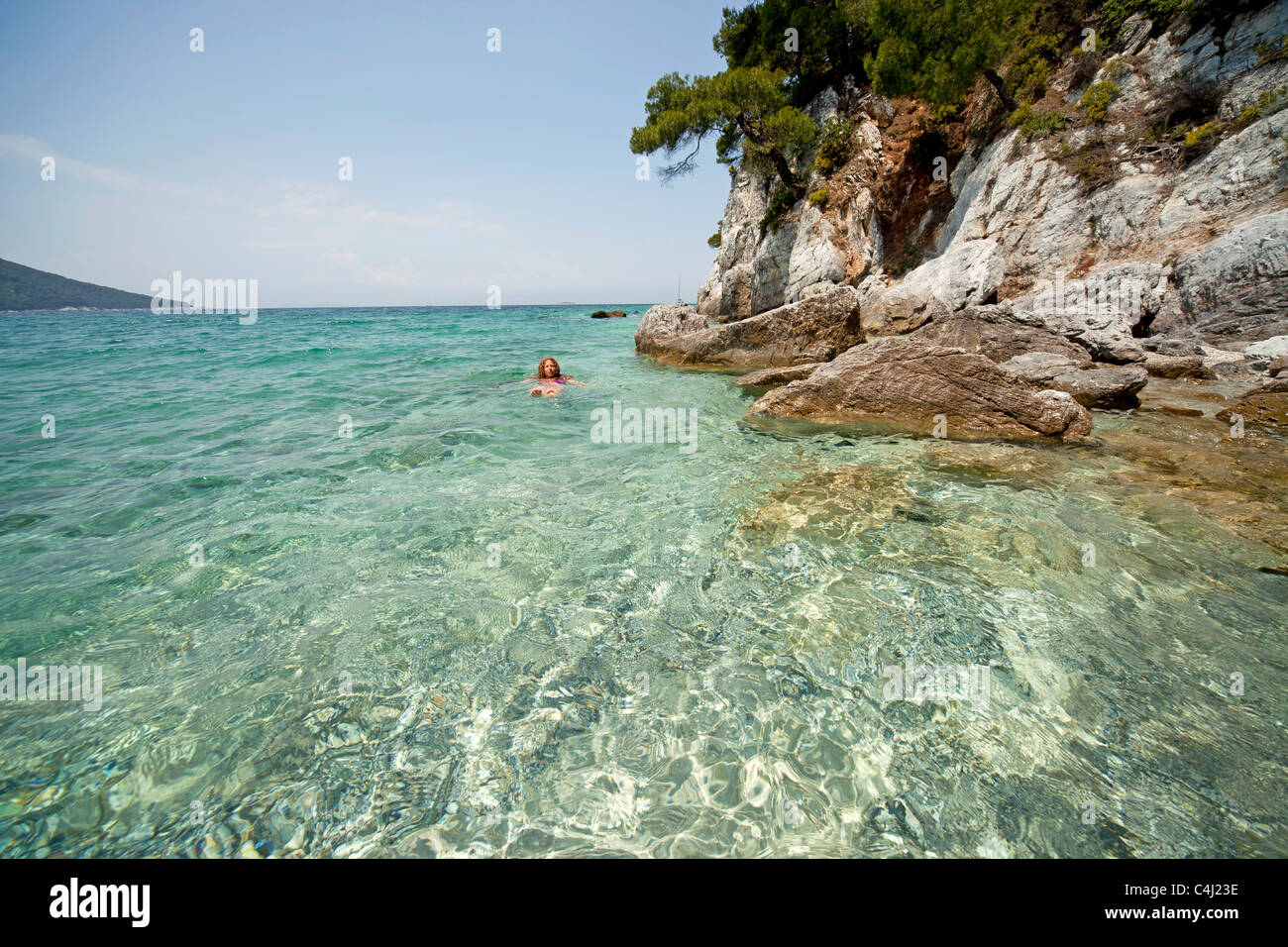 Jeune femme nageant dans l'eau claire de Gialos plage Kastani, Mamma Mia film emplacement sur l' île de Skopelos, Grèce Banque D'Images