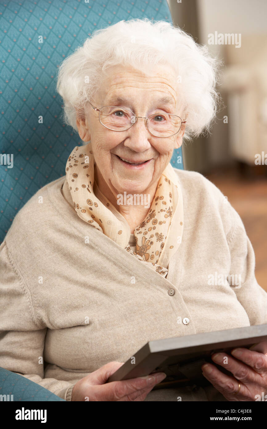 Senior Woman Looking At Photograph in Frame Banque D'Images