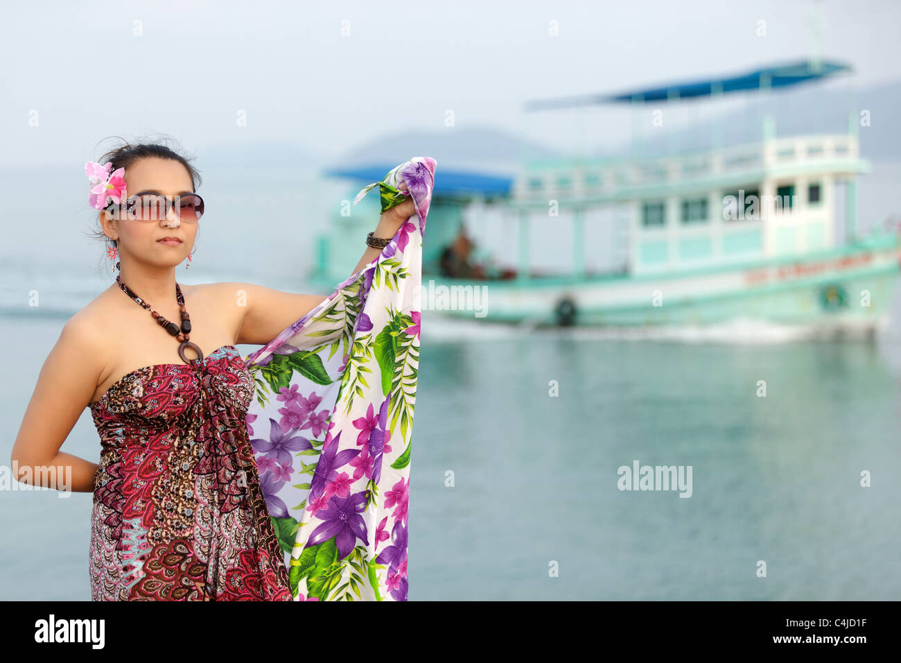 Asian woman holding sarong posant en mer avec le bateau à l'arrière-plan, Thaïlande Banque D'Images