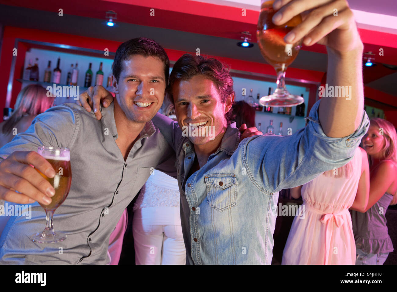 Deux jeunes hommes Having Fun In Busy Bar Banque D'Images