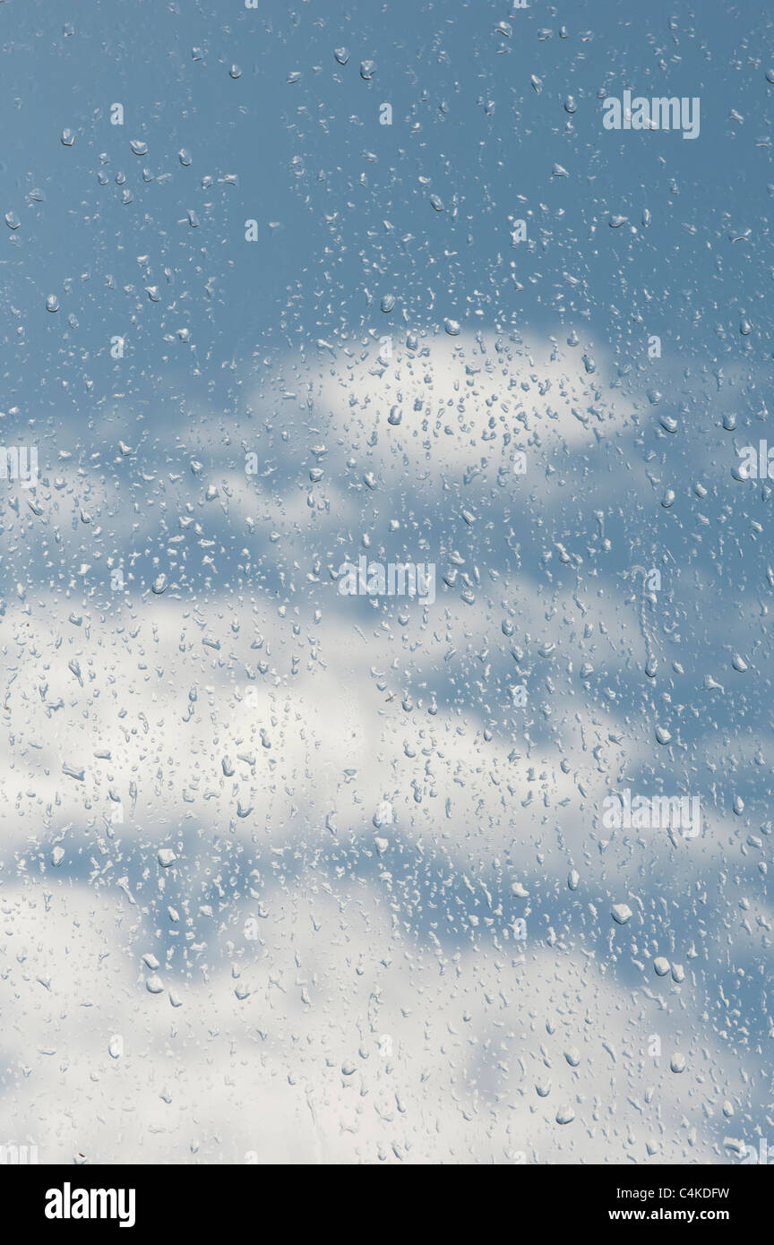 Gouttes de pluie sur une fenêtre en face d'un ciel nuageux ciel bleu Banque D'Images