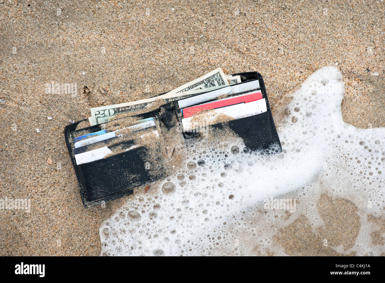 Un portefeuille perdu dans la zone de surf à la plage. Banque D'Images