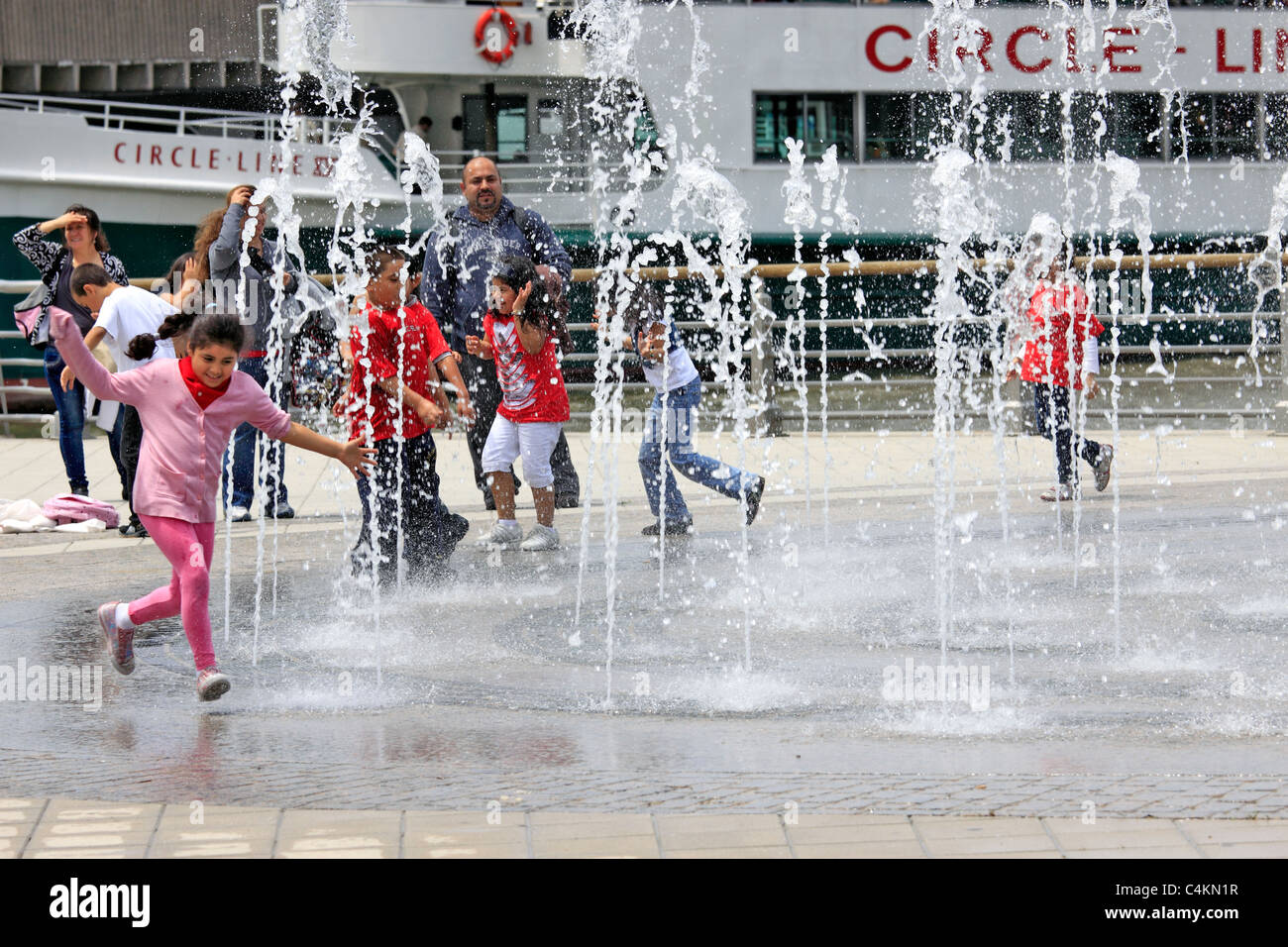 Enfants jouant dans l'eau arroseurs Circle Line Pier Manhattan New York Banque D'Images
