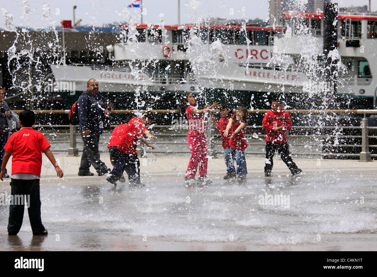 Enfants jouant dans l'eau arroseurs Circle Line Pier Manhattan New York Banque D'Images