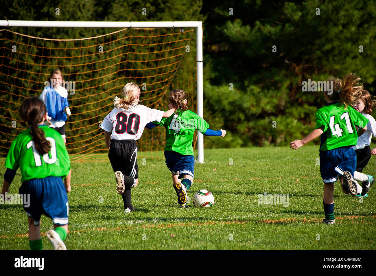 Fille de soccer pour les jeunes pousses balle à l'objectif. Banque D'Images