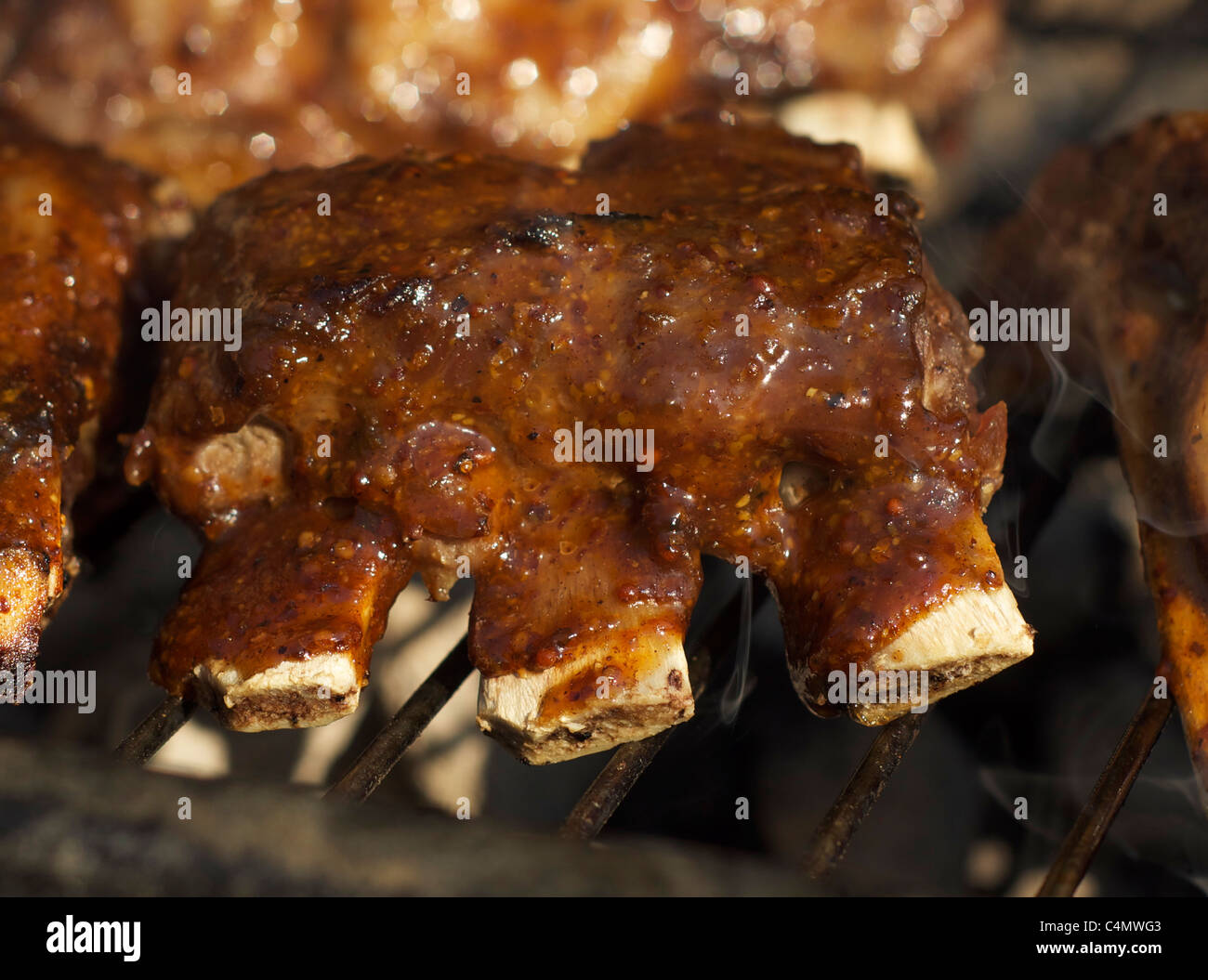 Côtes levées de porc cuisson sur un barbecue avec des flammes et de la fumée Banque D'Images