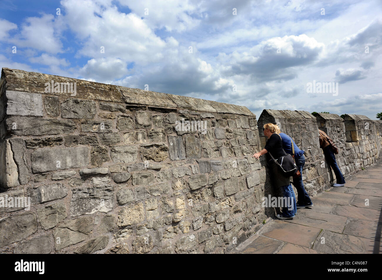Les touristes regarder à travers les lacunes dans les murs médiévaux qui entourent la ville de York Banque D'Images