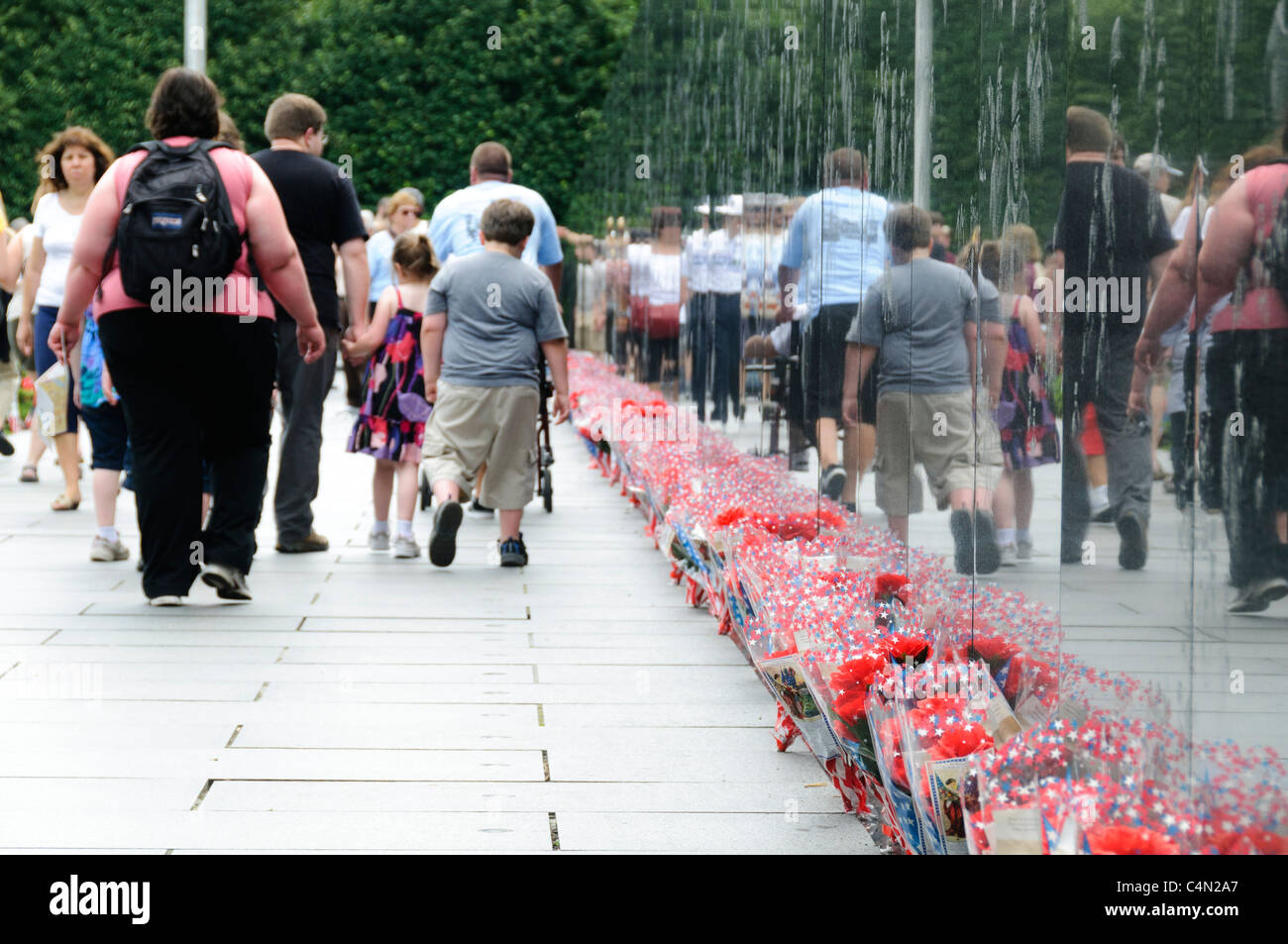 Mémorial des anciens combattants de la guerre de Corée bouquets de fleurs Washington DC // WASHINGTON DC — les visiteurs explorent le mémorial des anciens combattants de la guerre de Corée sur le National Mall tandis que des bouquets de fleurs bordent le mur réfléchissant de granit noir. Le mémorial présente 19 statues en acier inoxydable représentant des membres du service militaire américain. Le mur, qui s'étend sur 164 pieds de long, affiche des images photographiques de la guerre de Corée gravées dans sa surface. Banque D'Images