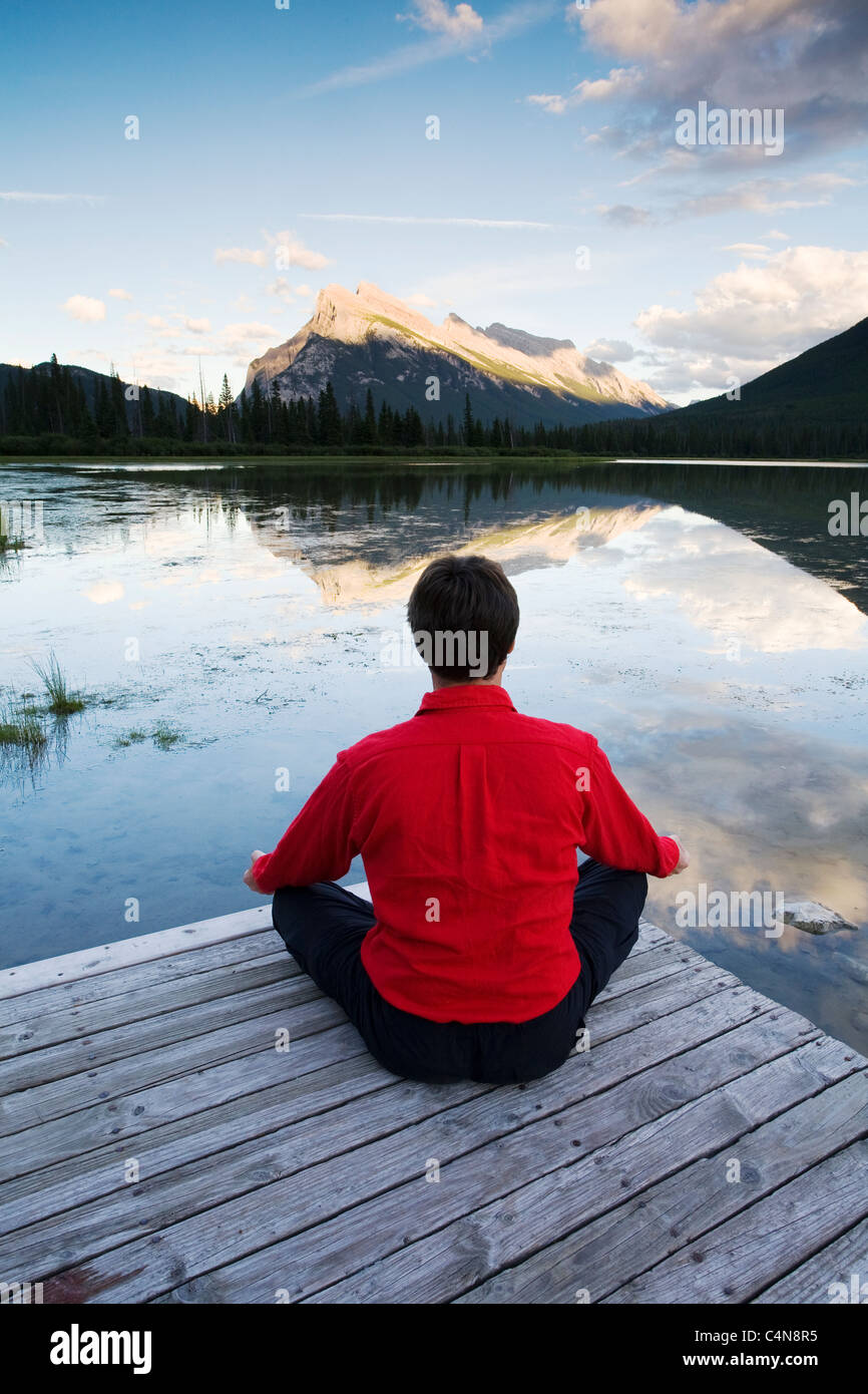L'âge moyen man meditating on dock à Vermillion Lake, Banff National Park, Alberta, Canada. Banque D'Images