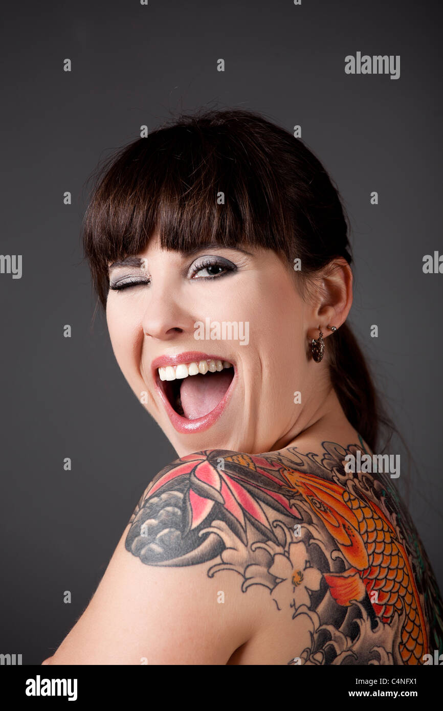 Portrait d'une belle jeune femme avec un tatouage sur le dos avec un clin d'yeux Banque D'Images