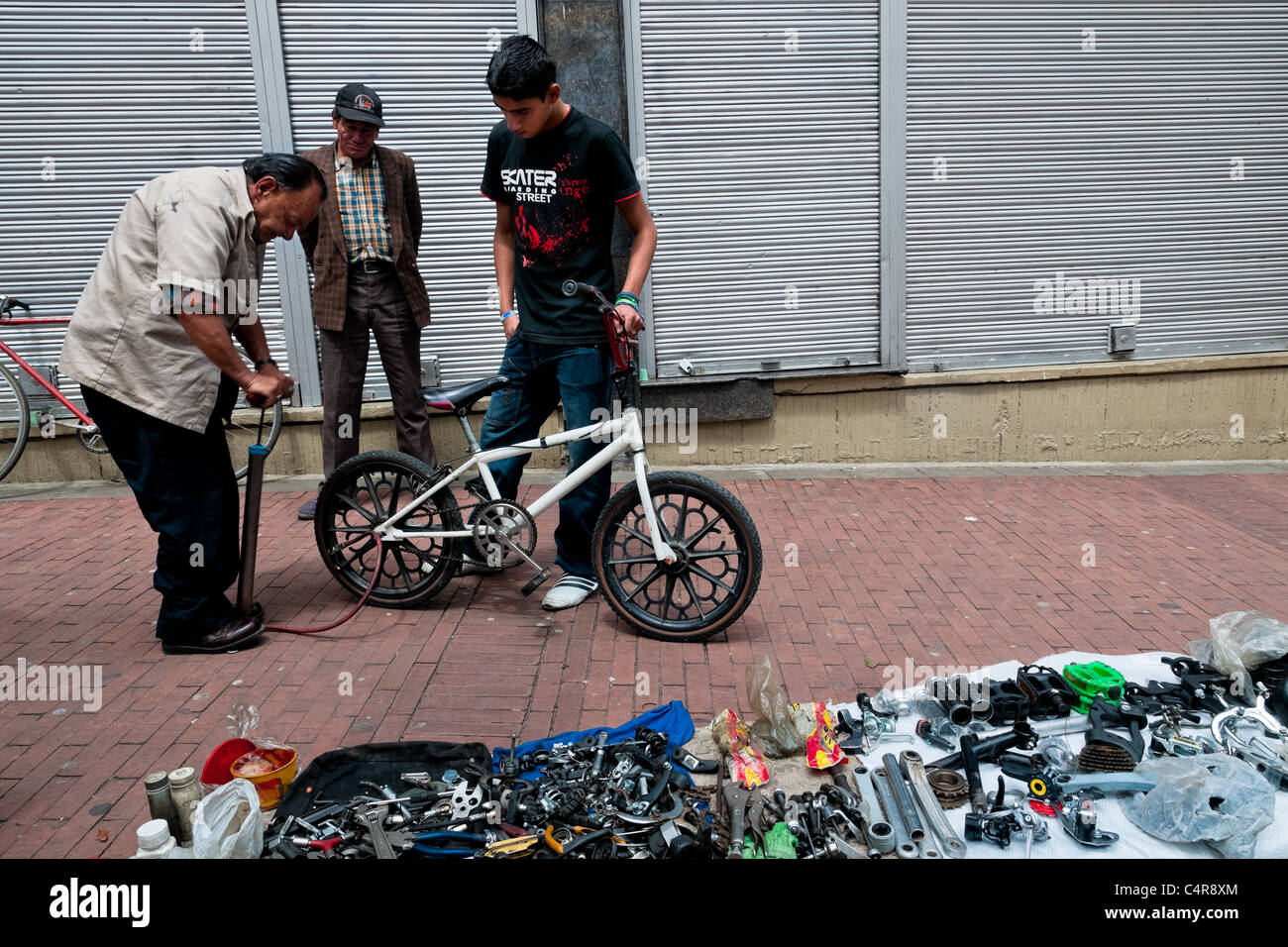 Un service de l'homme colombien de la pompes de vélo BMX pneu dans un atelier de réparation de vélos improvisé à Bogota, Colombie. Banque D'Images