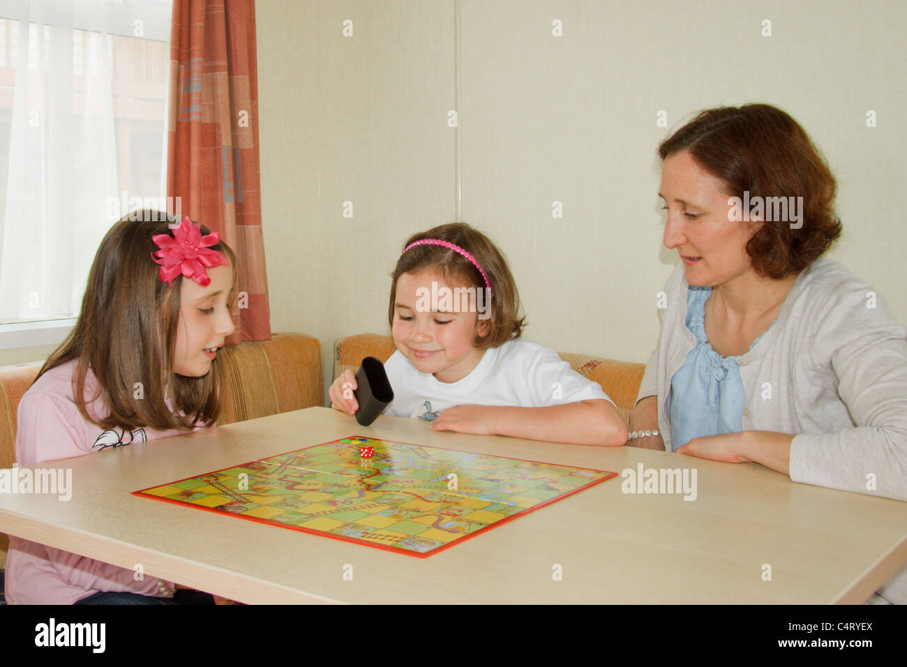 Family playing Snakes and Ladders en caravane Banque D'Images