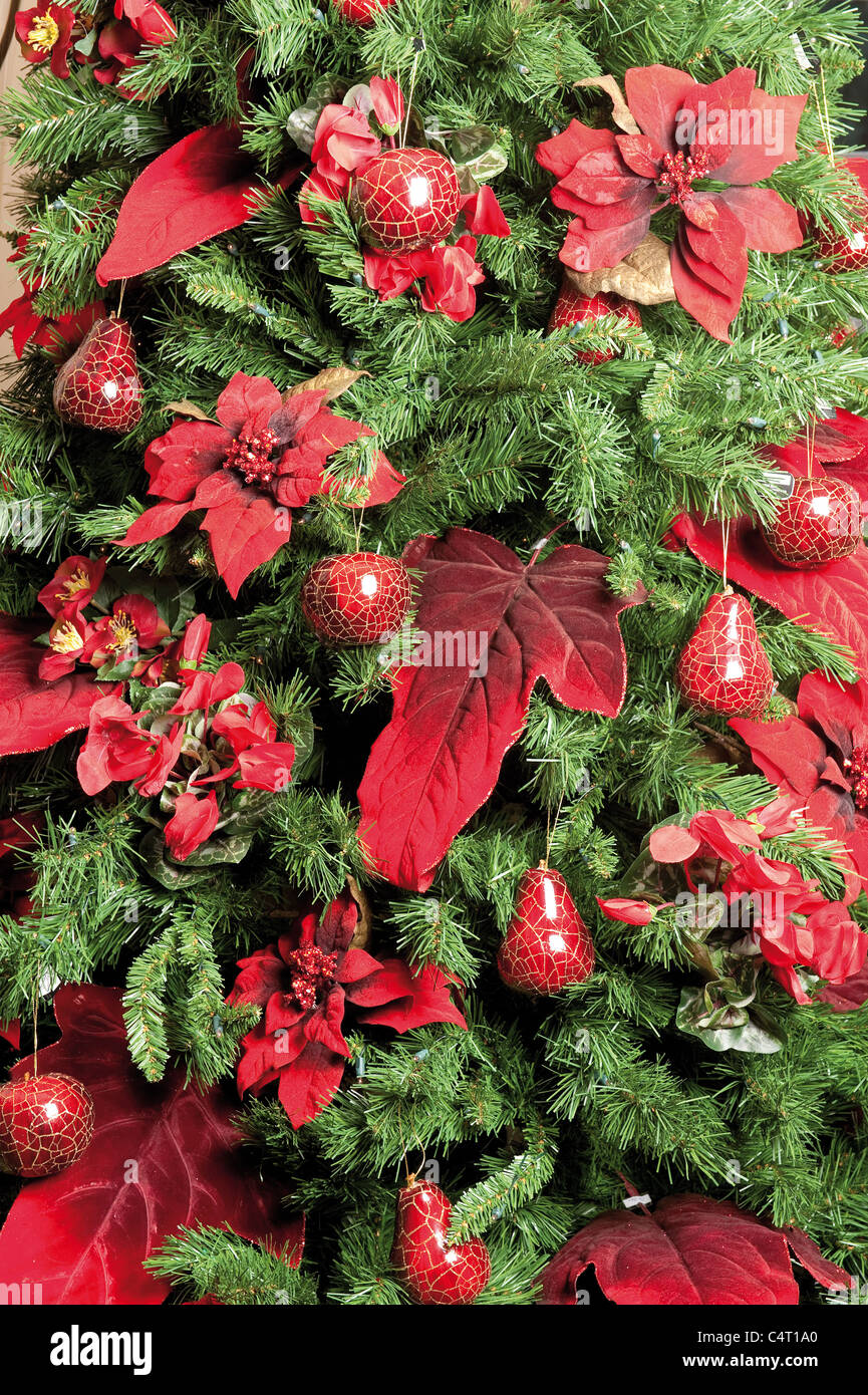 Arbre de Noël décoré de babioles et de plantes poinsettia rouge vert décorations babiole saisonnières traditionnelles Banque D'Images