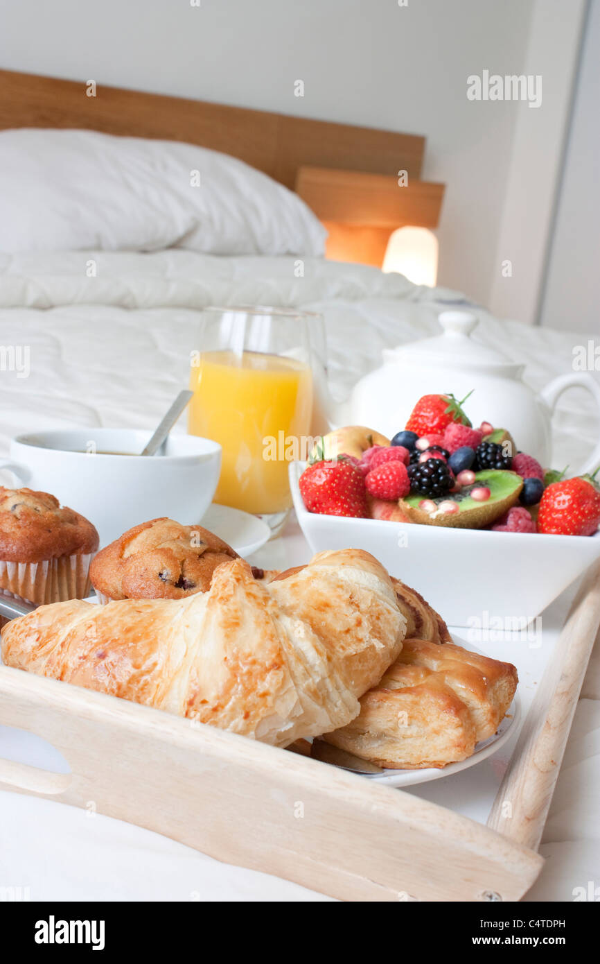 Plateau de petit-déjeuner mis en place sur un lit avec des aliments sains et des boissons Banque D'Images