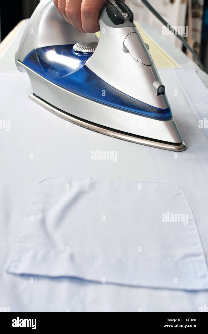 Gros plan du fer à repasser et table et d'appuyer sur une chemise empochée sur une planche à repasser. Banque D'Images