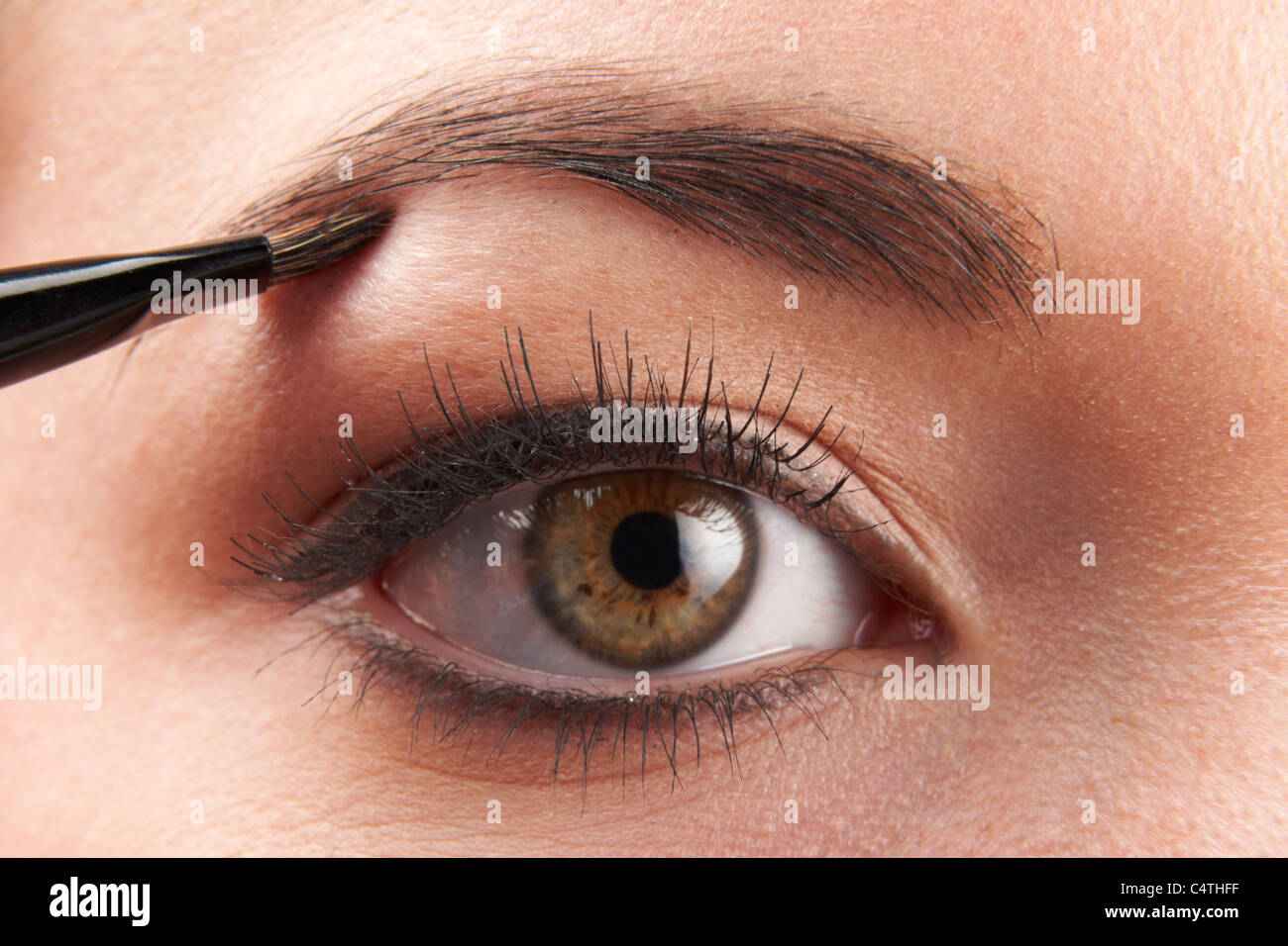 Woman applying eye make-up avec la brosse sur fond blanc Banque D'Images