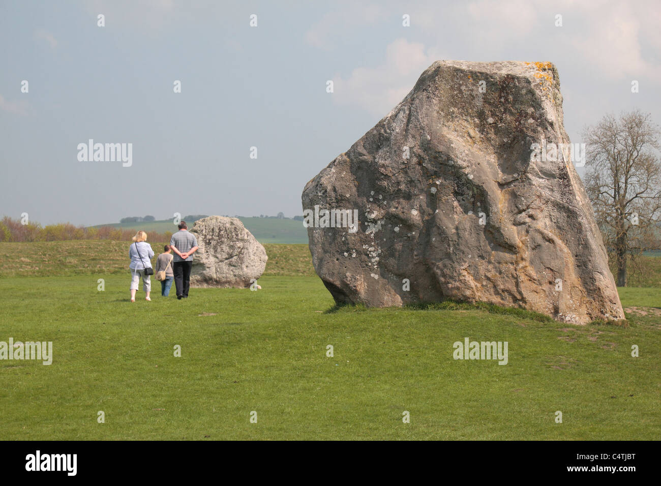Visiteurs marchant à côté du cercle intérieur des menhirs. Une partie de l'Avebury Henge & Stone Circles site, Wiltshire, Angleterre. Banque D'Images