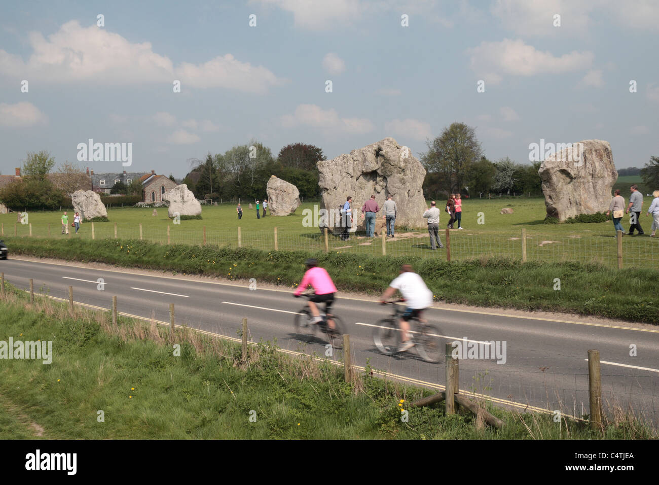 Les cyclistes sur la route A4361 fonctionnant par les cercles de pierre d'Avebury Henge & site, Wiltshire, Angleterre. Banque D'Images