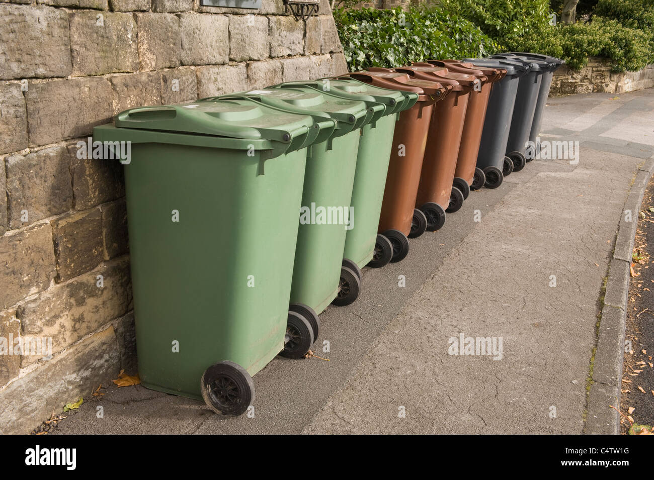 Poubelles à roulettes (gris brun vert) pour déchets domestiques, recyclage et déchets de jardin alignées sur la chaussée pour la collecte - Leeds, Yorkshire, Angleterre, Royaume-Uni. Banque D'Images