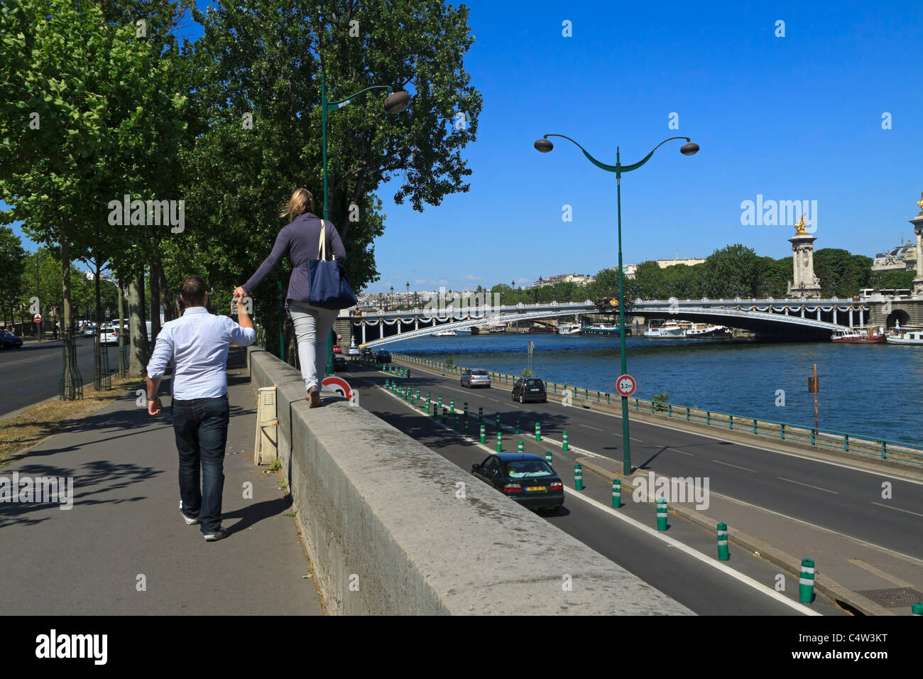 Sites touristiques de Paris. Un couple marche le long du quai d'Orsay à côté de la Seine vers le Pont Alexandre III. Banque D'Images