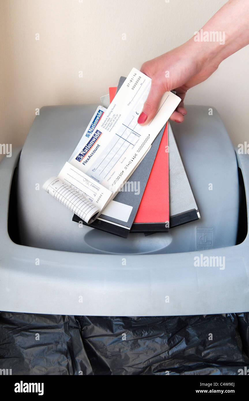 Image montrant la main de femme caucasienne vérifier books être jeté dans le bac indiquant le retrait de chèques au Royaume-Uni Banque D'Images