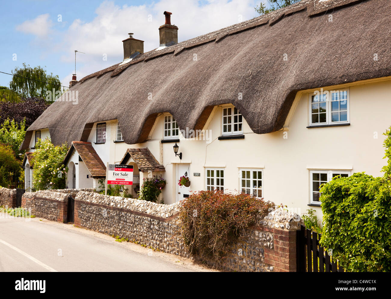 Maison de chaume UK - Old English semi-détaché / terrasse dans un petit village, un cottage de chaume avec un panneau pour la vente, Angleterre UK Banque D'Images