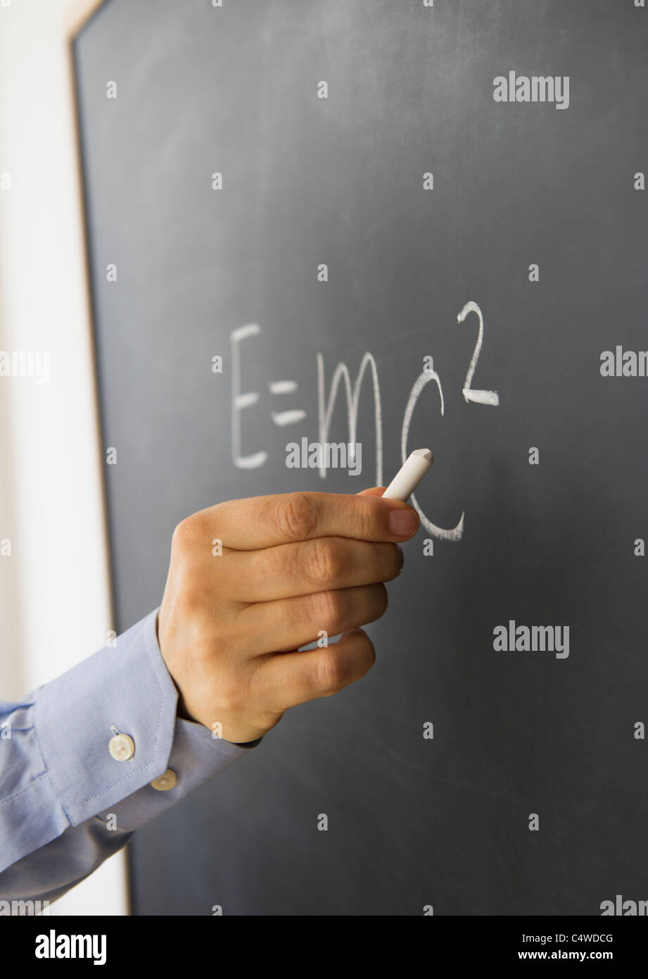 Close-up of man's hand writing formule la théorie de la relativité sur tableau noir Banque D'Images