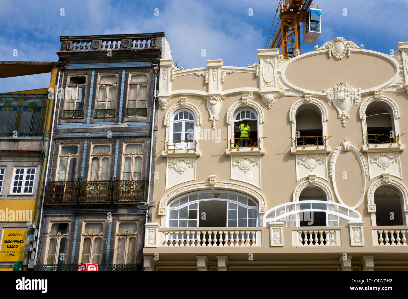 Un constructeur montage d'une fenêtre pour un nouveau bâtiment à Porto. Peu de la santé et de la sécurité. Grue avec grand angle. Banque D'Images