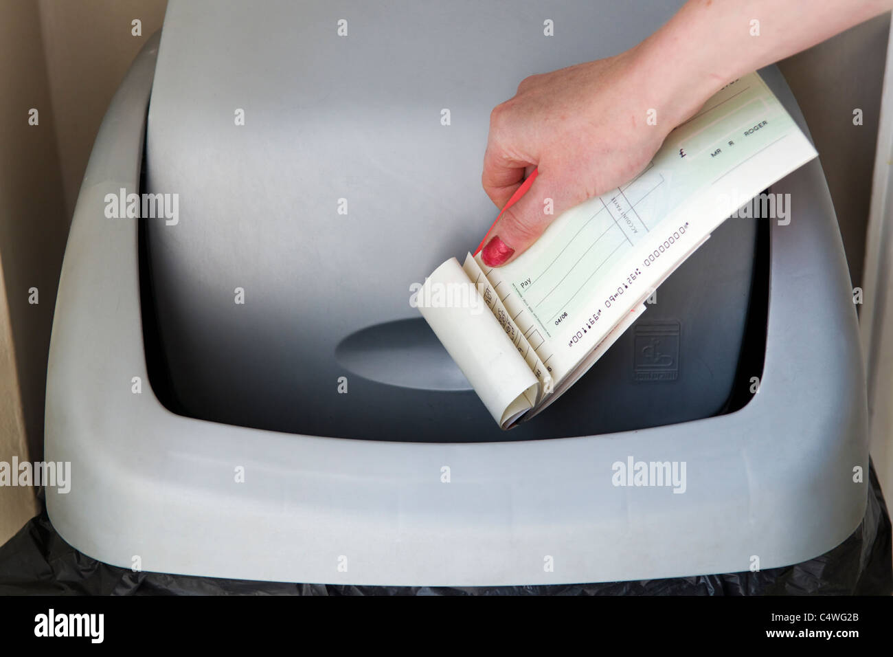 Image montrant la main de femme caucasienne vérifier books être jeté dans le bac indiquant le retrait de chèques au Royaume-Uni Banque D'Images
