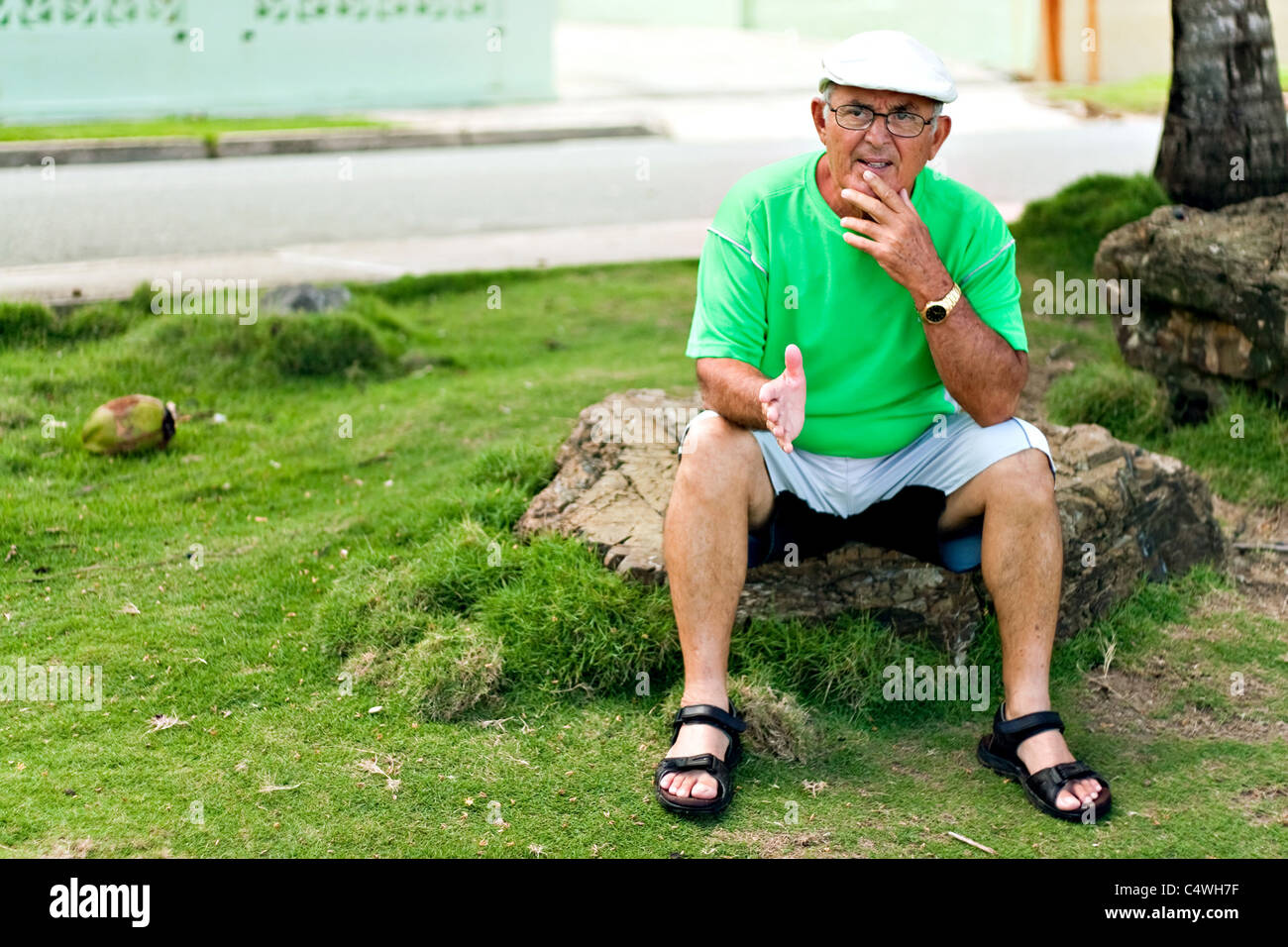 Plus d'un Senior citizen hispanique homme est assis à l'extérieur dans un cadre tropical. Banque D'Images