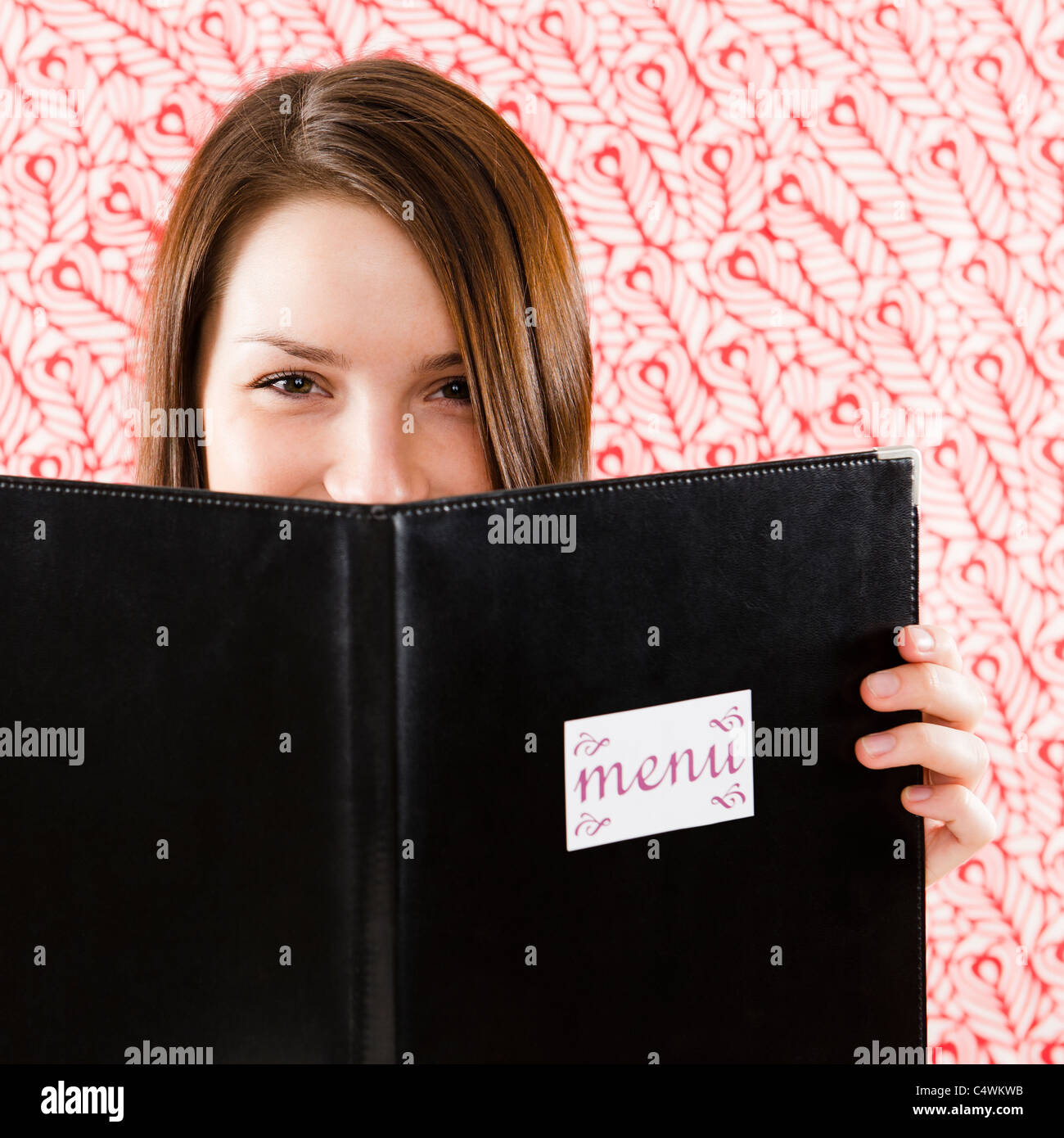 USA,New Jersey, Jersey City,Portrait of smiling young woman holding restaurant menu en face de visage Banque D'Images