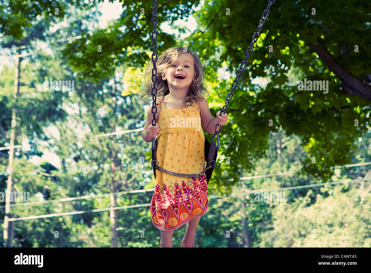 USA,Michigan,Charlevoix,Girl (2-3) on swing in playground Banque D'Images