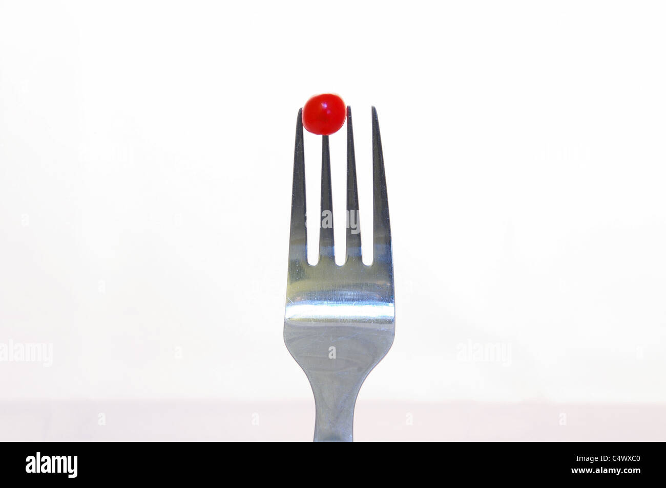 Fourchette métallique avec un pois ou de petits fruits rouges avec un fond clair Banque D'Images