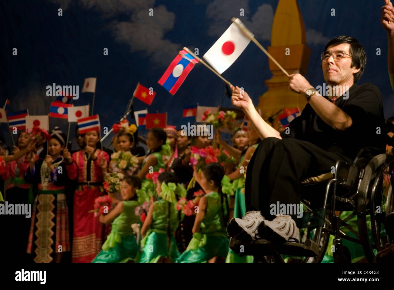 Un homme handicapé dans un fauteuil roulant s'agitaient des drapeaux pendant un spectacle marquant la Journée internationale pour les personnes handicapées au Laos. Banque D'Images