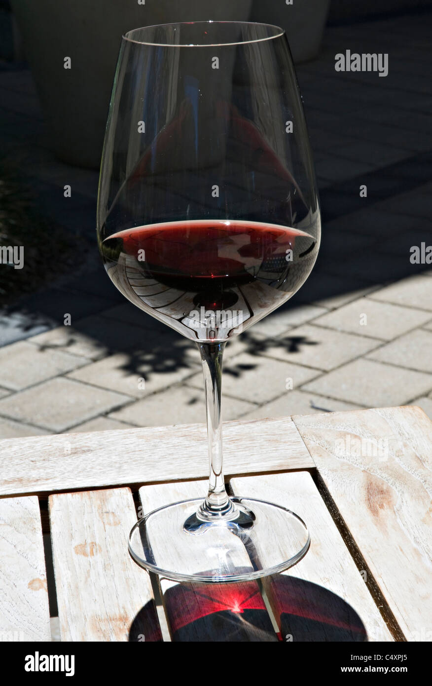 Un verre de vin rouge avec des réflexions sur une table de pique-nique au Centre National du vin à Adelaide (Australie) Banque D'Images